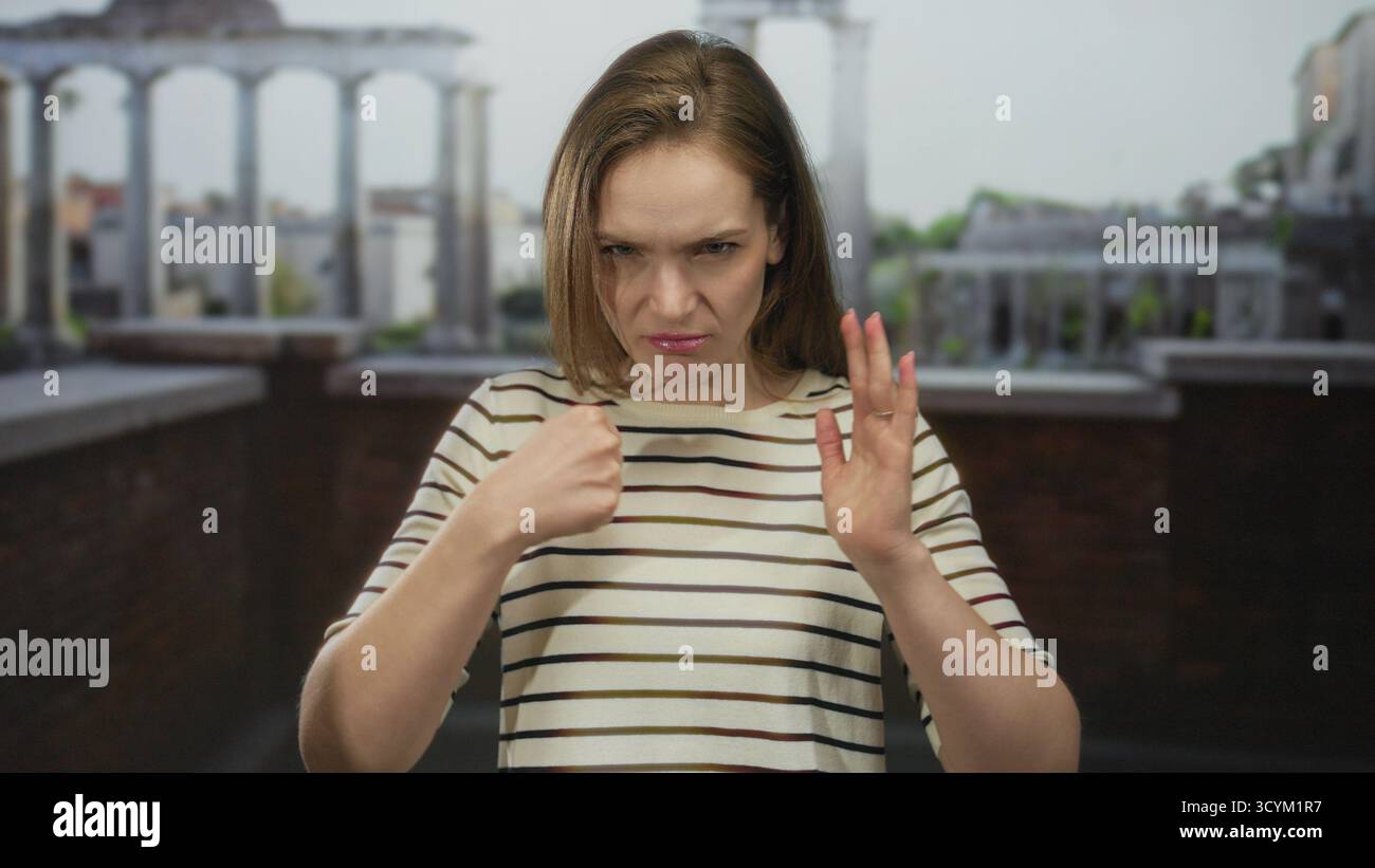 Junge Frau zeigt mit dem Finger direkt auf die Kamera im antiken römischen Gebäude; Wut Spannung Trotz Frustration. Stockfoto