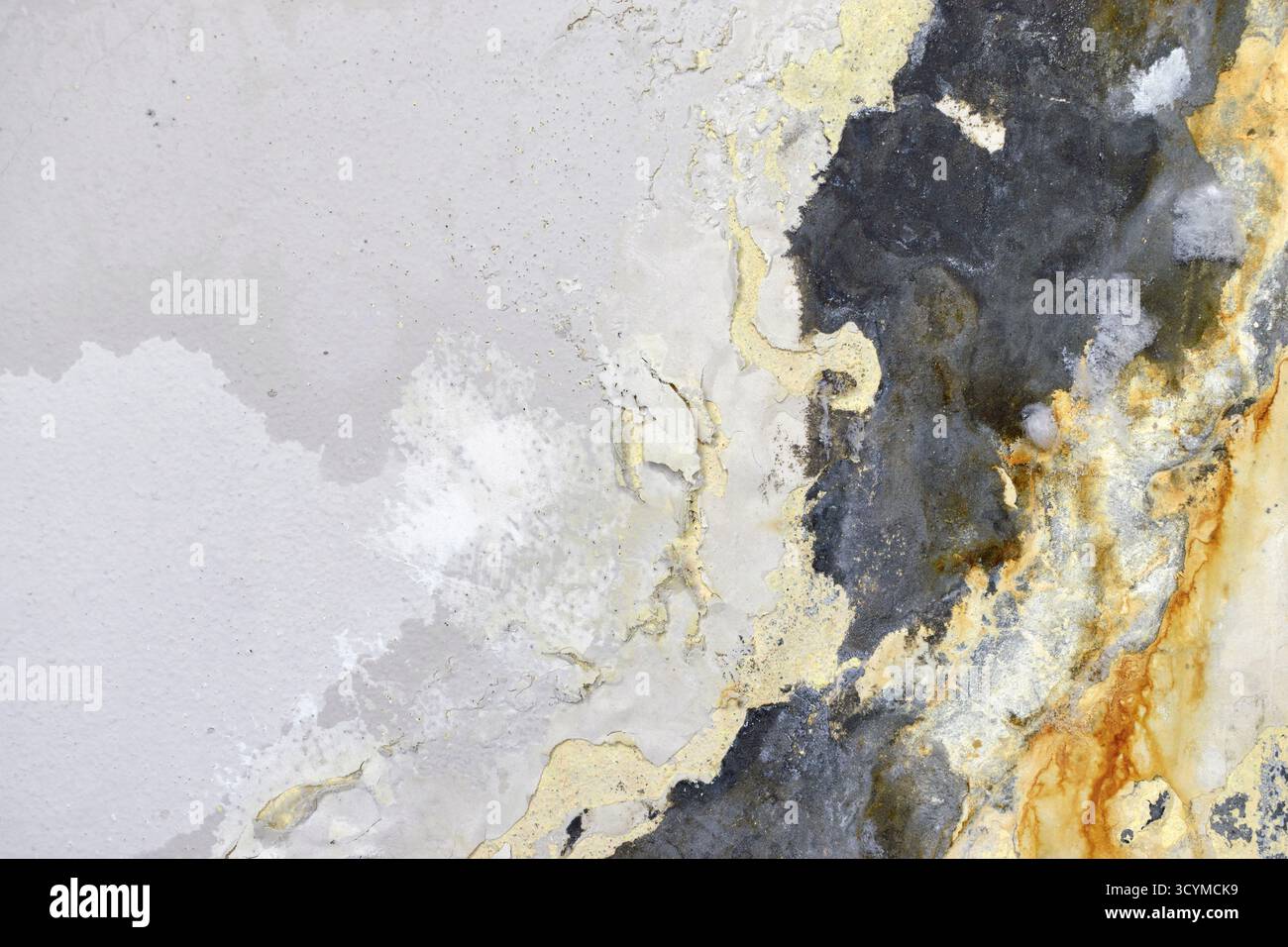 Korrodierte Wand mit gelben und grauen Feuchtigkeitsflecken. Stockfoto