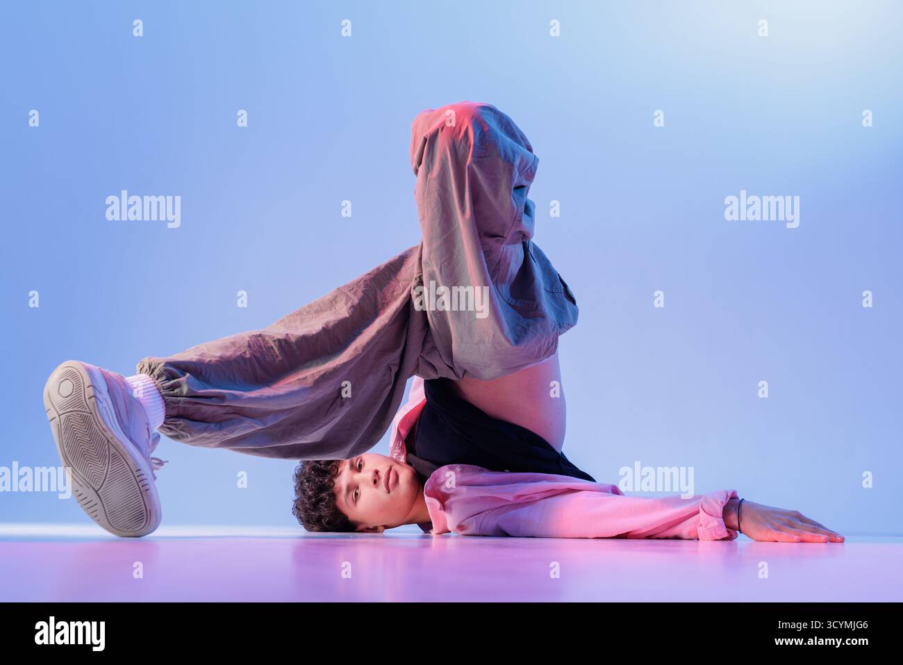 Young Breaker sorgt für ein extremes Floor-Freeze unter rosa blauen Lichtern, modernen urbanen Stil für Musik-Visuals, Veranstaltungen, Anzeigen und Kampagnen zur Jugendkultur. Stockfoto