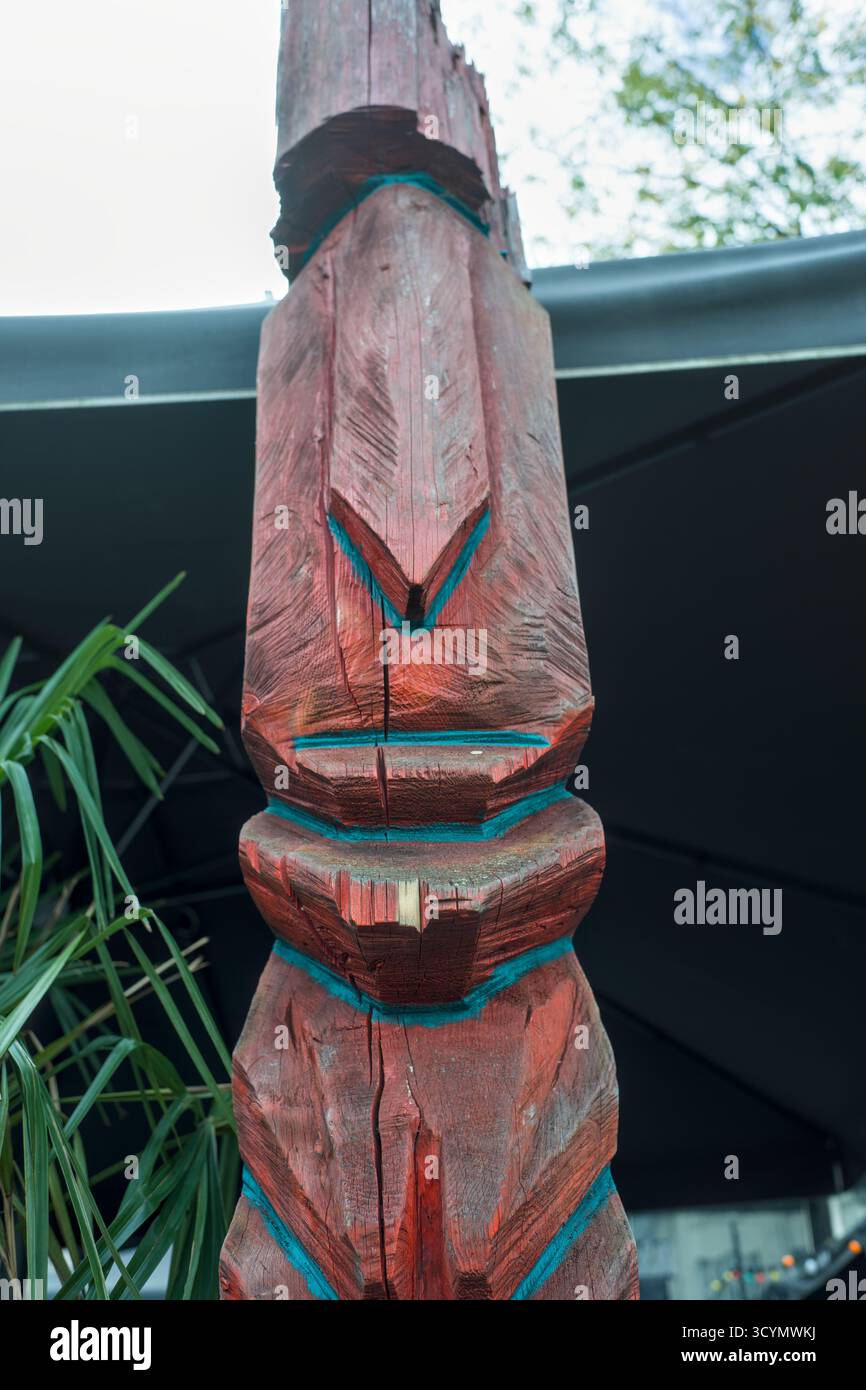 Nahaufnahme einer überwiegend roten Tiki-Figur aus Holz, die in einem urbanen Umfeld in einer deutschen Stadt gezeigt wird. Stockfoto