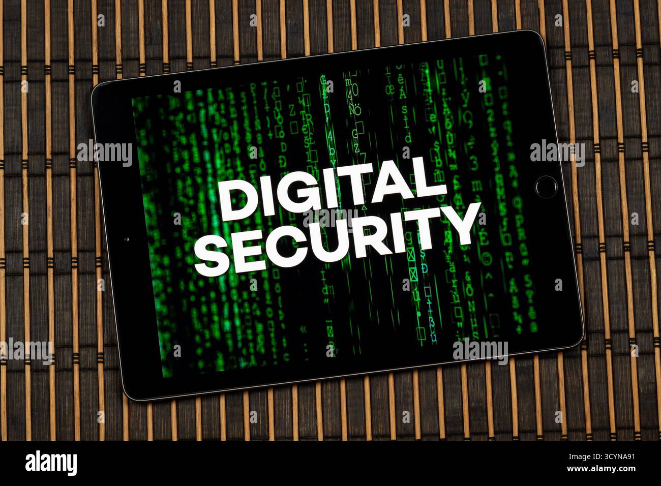Nahaufnahme eines digitalen Tablets mit dem Satz digitale Sicherheit über grünem digitalem Code und hölzernem Hintergrund Stockfoto