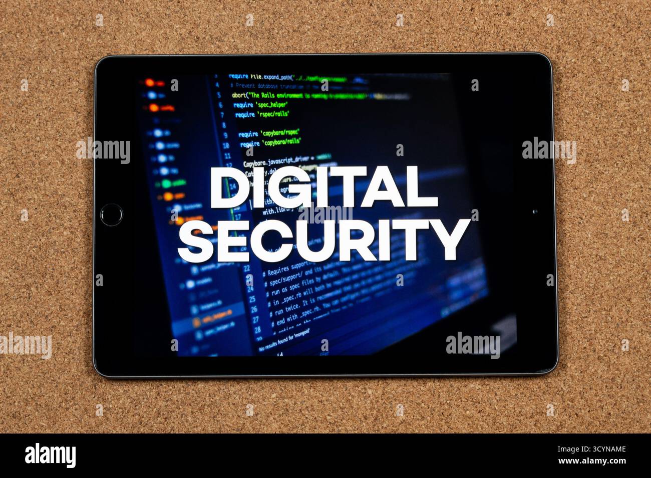 Nahaufnahme eines Tablets mit dem Satz digitale Sicherheit über einem Schreibcode-Konzept und einem Korkhintergrund Stockfoto