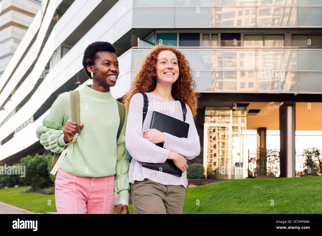 Zwei junge Studenten lächeln und gehen die Straße runter Stockfoto