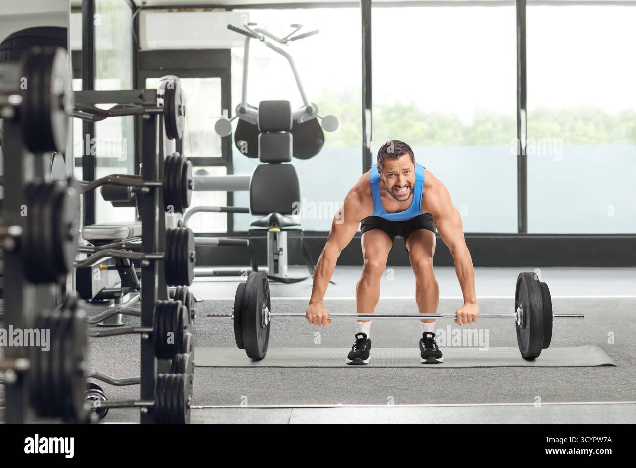 Bodybuilder in einem Fitnessstudio, der schwer mit schweren Gewichten zu kämpfen hat Stockfoto