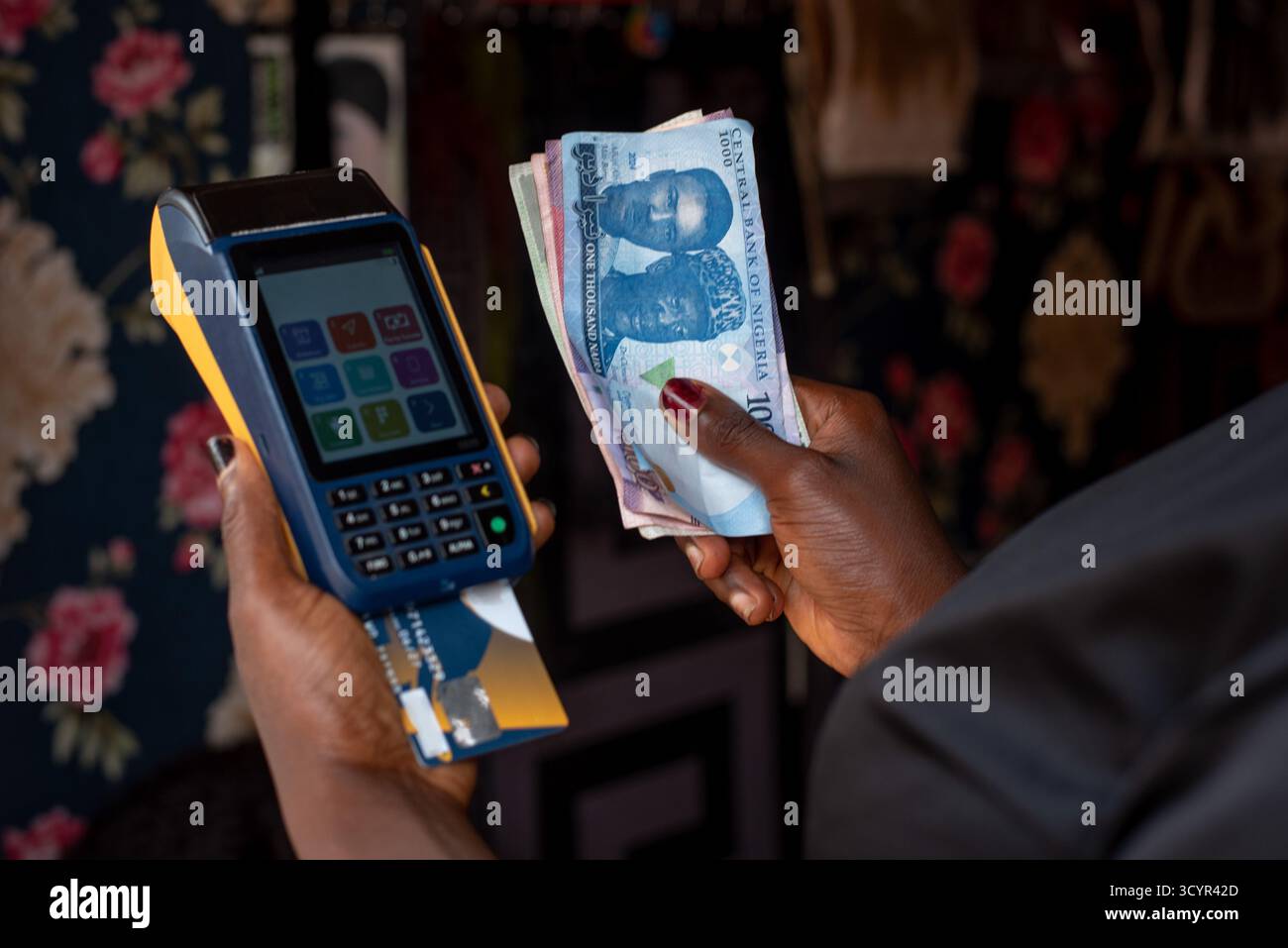 Die Friseurin Omolara Taiwo hält am Dienstag, den 11. Juni, einen POS-Automaten und Banknoten in ihrem Geschäft im Bundesstaat Oyo, Nigeria, bereit. 2024. Stockfoto