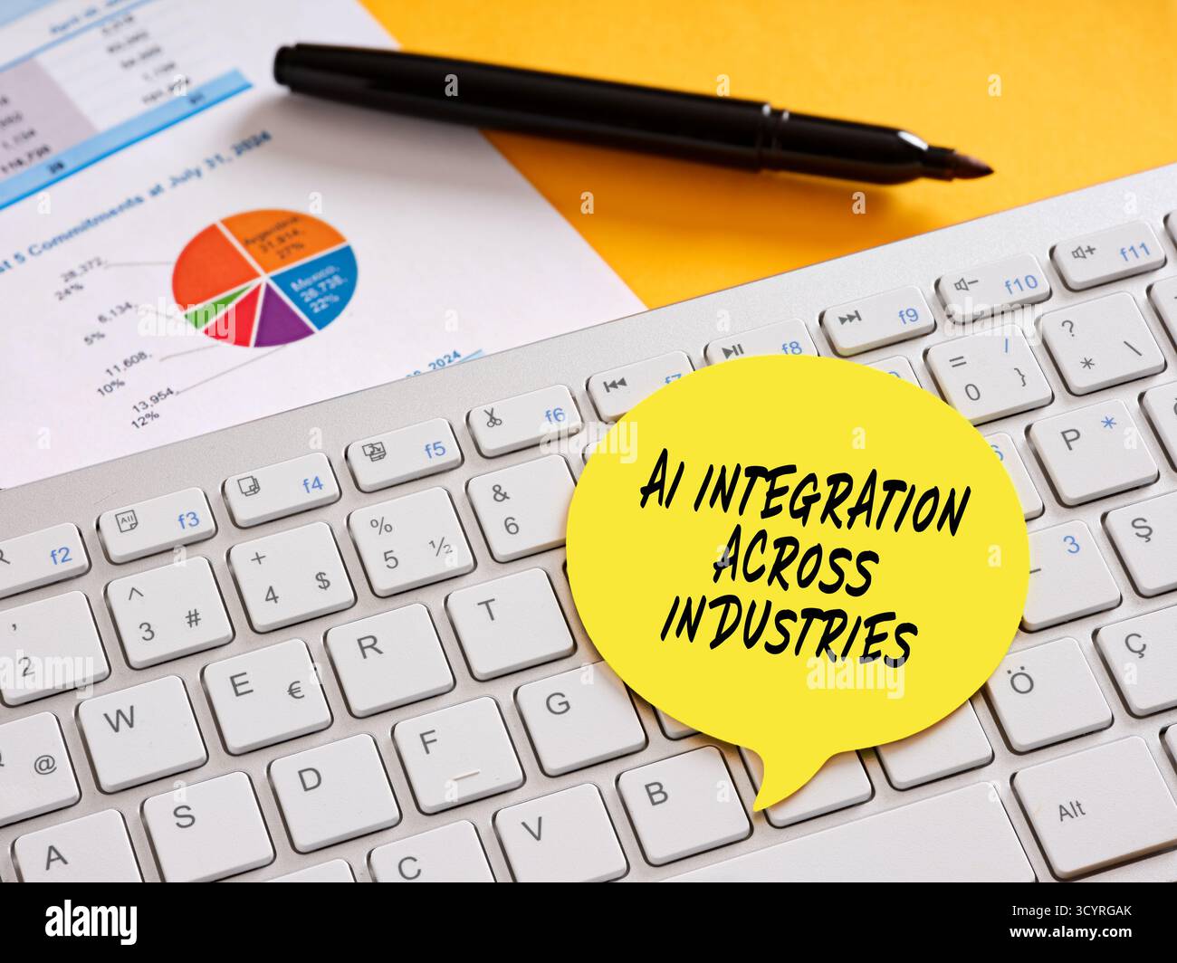 Gelbe Sprechblase mit branchenübergreifender AI-Integration auf Computertastatur mit Diagramm und Stift auf gelbem Hintergrund Stockfoto