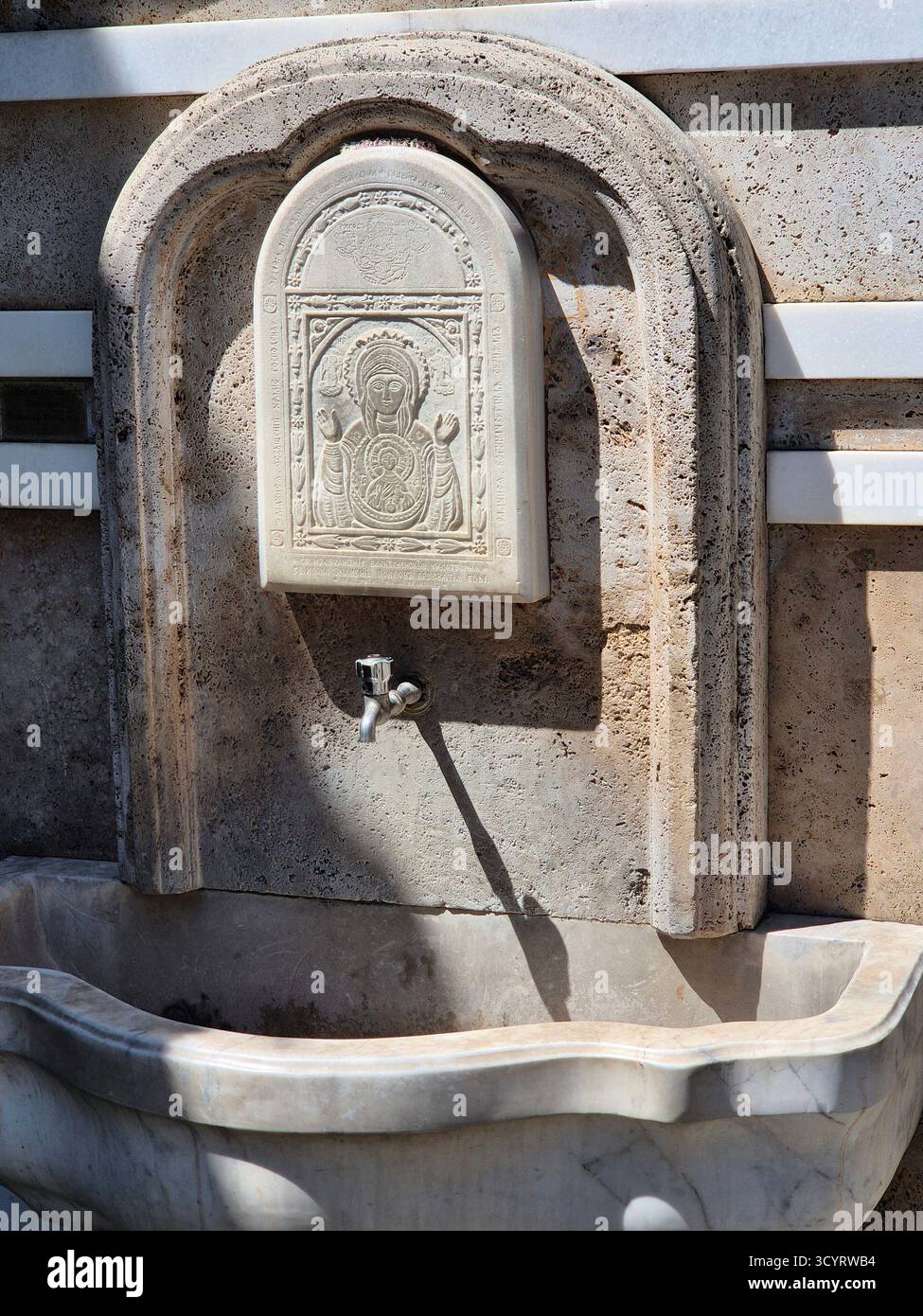 Quelle der Gnade. Ein Ort der Weihe und des reinen Wassers im Innenhof einer Kirche oder eines Klosters - Smartphone-aufgenommenes Stockfoto