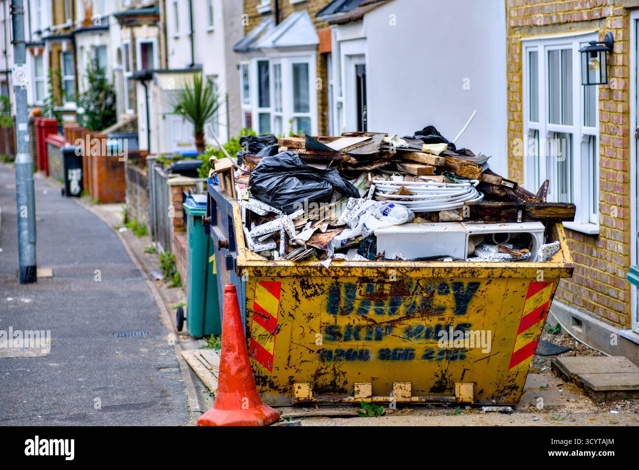 Überspringen voller Müll vor dem Haus Ready for Collection, Watford, Hertfordshire, England, Großbritannien Stockfoto