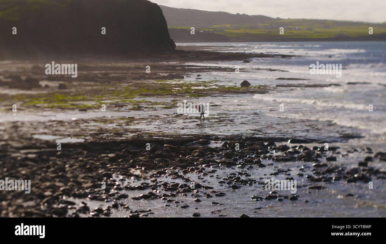 Surfer an der Westküste Irlands unterhalten sich in der felsigen Ebbe kurz. Stockfoto