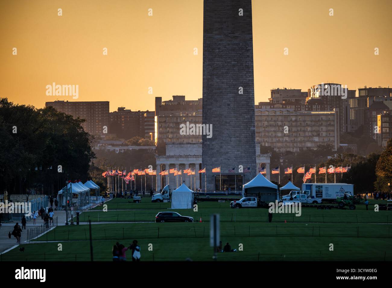 Washington DC // WASHINGTON DC – das Washington Monument wird bei Sonnenaufgang auf der National Mall mit einer Reihe amerikanischer Flaggen im goldenen Licht beleuchtet. Dieser berühmte Obelisk, der dem ersten US-Präsidenten George Washington gewidmet ist, ist ein prominentes Wahrzeichen der Hauptstadt. Mit einer Höhe von 169,29 Metern (555 Fuß 5 1/8 Zoll) ist er das höchste Steinbauwerk und Obelisk der Welt. Die National Mall ist ein bedeutender Nationalpark und Freilichtmuseum, das vom National Park Service verwaltet wird. Es erstreckt sich vom Lincoln Memorial bis in die USA Stockfoto