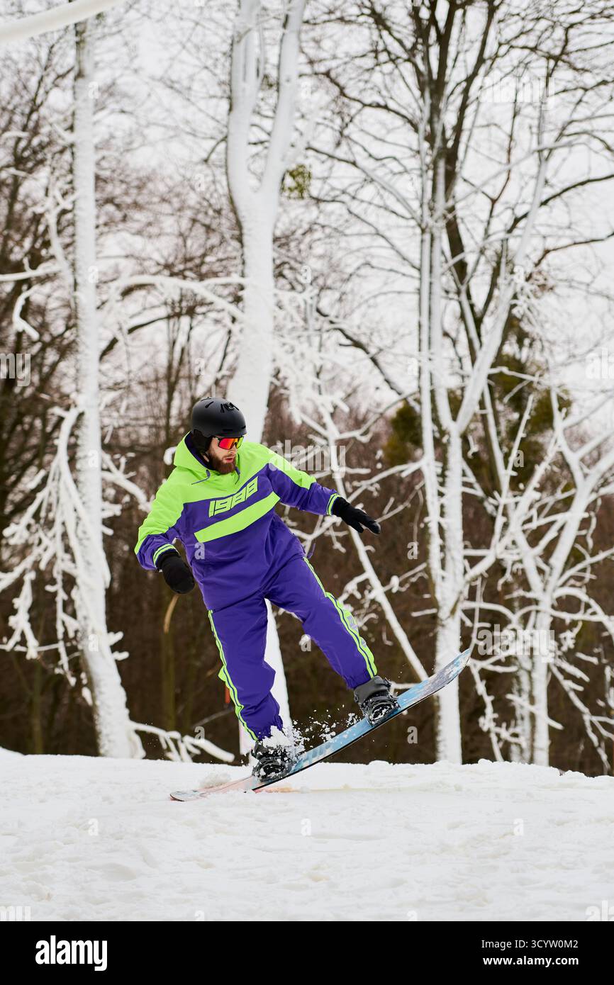 Ein bärtiger Mann genießt im Winter Snowboarden auf einer verschneiten Piste, die von Bäumen umgeben ist. Stockfoto
