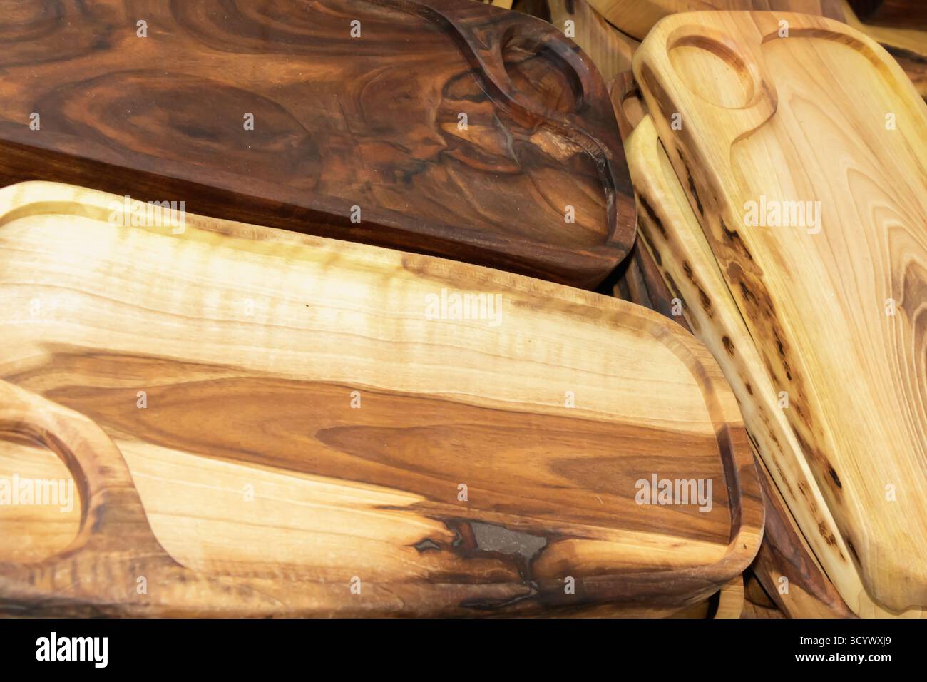 Eine Nahaufnahme handgefertigter Holzschneidebretter mit natürlichen Texturen und satten Holzmaserungen. Die warmen Töne unterstreichen feine Handwerkskunst und Stockfoto