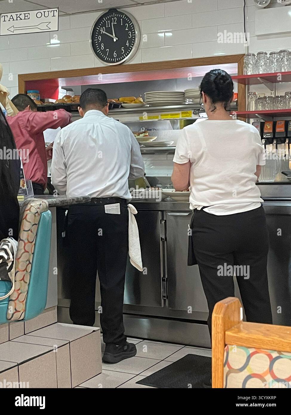 Kellner und Kellnerin warten auf ihre Bestellungen im Murray Hill Diner Pick Up Window, 2025, New York City, USA - Smartphone-aufgenommenes Stockfoto