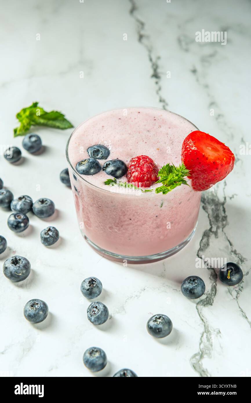Fest strukturierte Heidelbeeren und ein Smoothie mit Blaubeeren und Camu-Camu auf einem Tisch aus Pinienholz Stockfoto