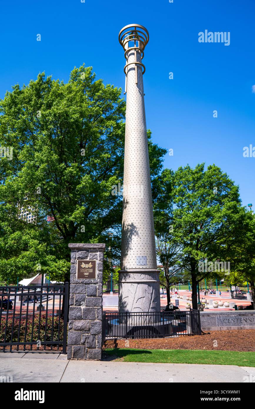 Am Eingang des Centennial Olympic Park steht eine hohe Olympiakolonne, die von üppigen grünen Bäumen und hellblauem Himmel im Zentrum von Atlanta umgeben ist Stockfoto
