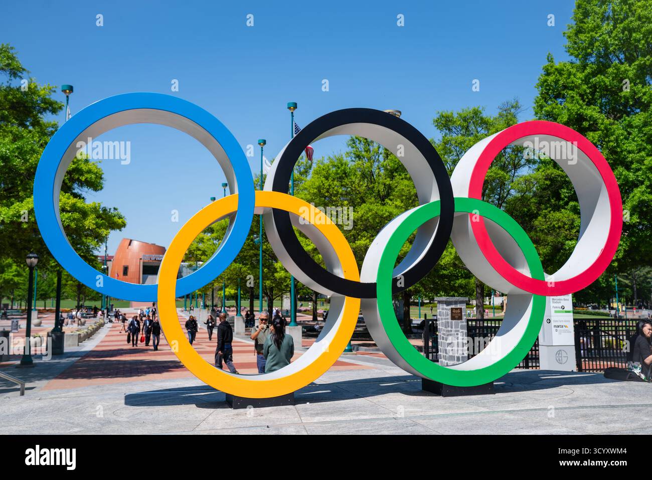 Touristen besuchen den Centennial Olympic Park und posieren für Fotos mit dem berühmten Denkmal der Olympischen Ringe an einem hellen Frühlingstag in der Innenstadt von Atlanta Stockfoto
