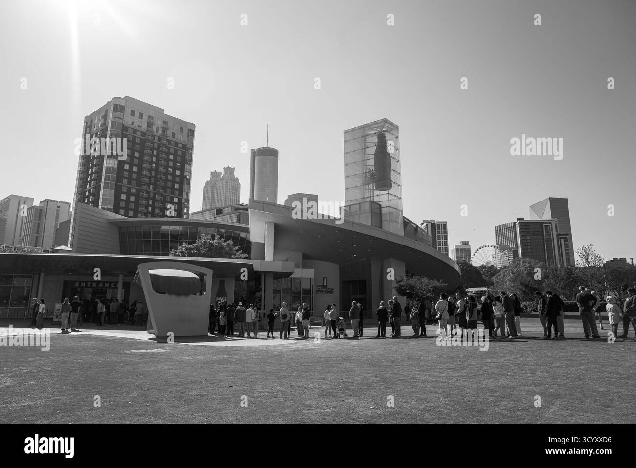Besucher stehen an einem sonnigen Morgen vor der World of Coca-Cola am Pemberton Place, unter der Skyline von Atlanta in Schwarz-weiß Stockfoto
