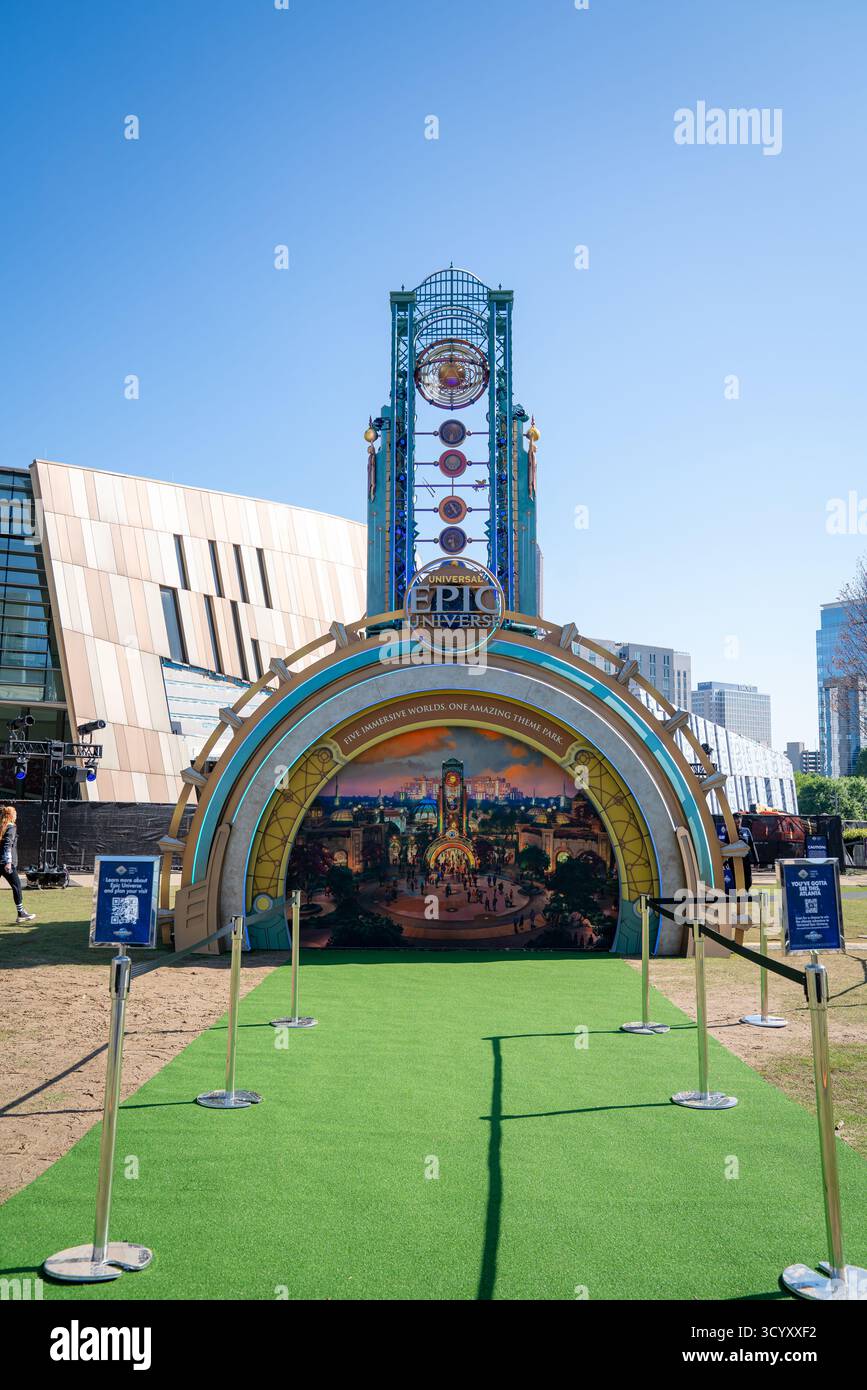 Die Ausstellung des Universal Epic Universe mit seinem bogenförmigen Eingang und dem beleuchteten Turm lädt Besucher auf einem leuchtend grünen Fußweg ein Stockfoto