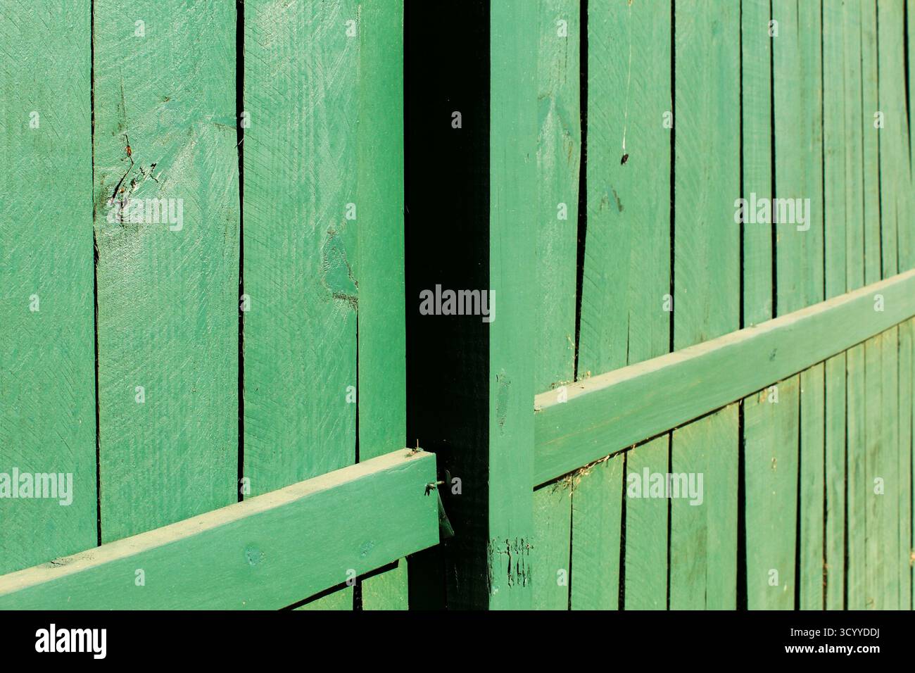 Abgenutzter grüner Holzzaun mit Schatten und Linien Stockfoto