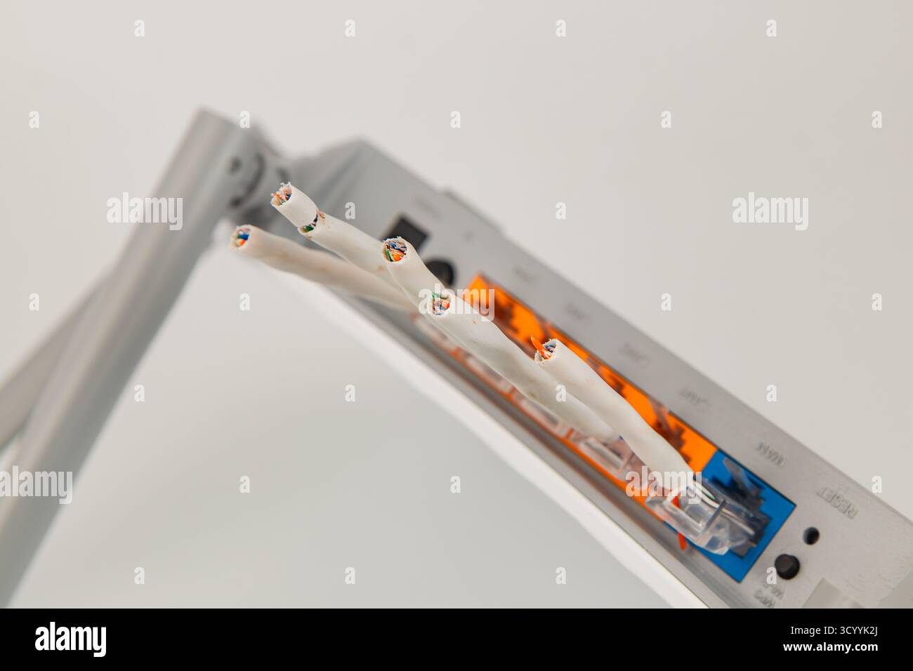 Ein Netzwerk-Router wird in einem Seitenwinkel dargestellt und zeigt mehrere Anschlüsse und Kabel. Das Gerät wird vor einem einfachen Hintergrund, hervorgehoben, gestellt Stockfoto