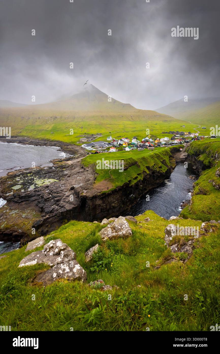 Vertikaler Blick auf das kleine Dorf Gjogv an einem bewölkten Frühlingstag. Eysturoy, Färöer, Dänemark, Europa. Stockfoto