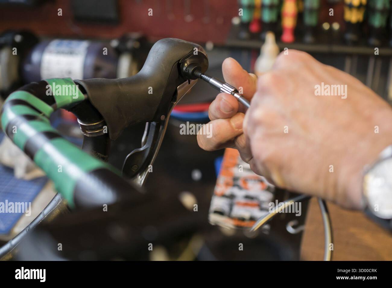 Foto von Guy, der den Fahrradgriff mit einem Schraubendreher fixiert Stockfoto