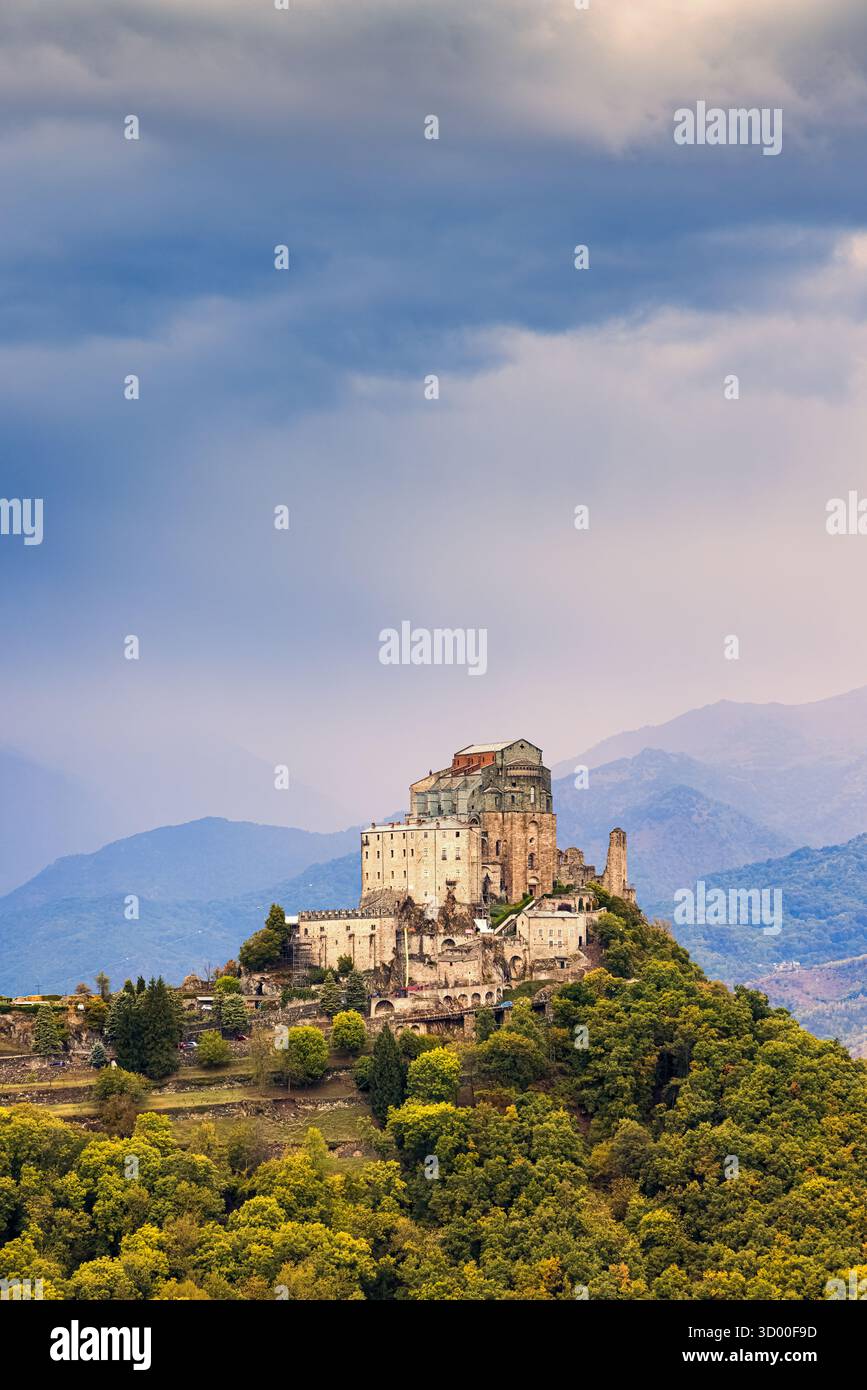 Ein malerischer Bergpfad schlängelt sich durch das üppige Grün der piemontesischen Alpen, mit Blick auf die imposante Sacra di San Michele, die mA steht Stockfoto Ein malerischer Bergpfad schlängelt sich durch das üppige Grün der piemontesischen Alpen, mit Blick auf die imposante Sacra di San Michele, die mA steht Stockfoto