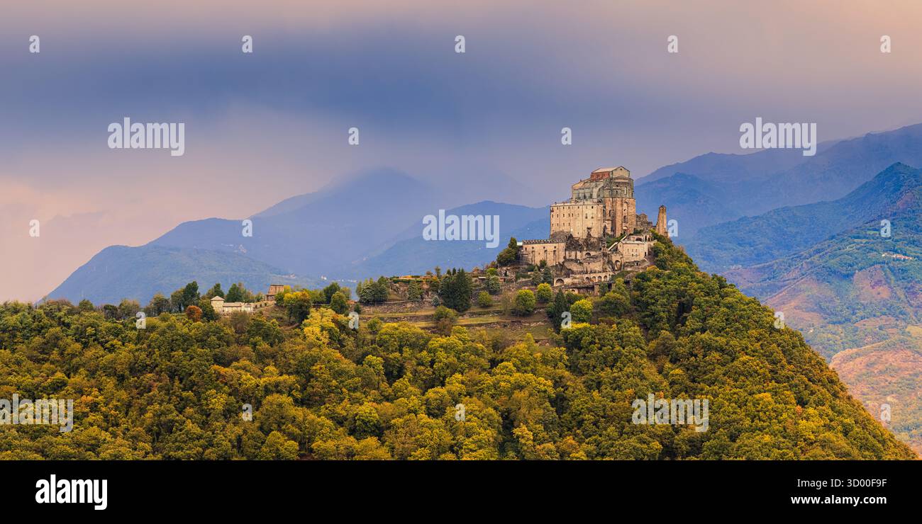 Ein malerischer Bergpfad schlängelt sich durch das üppige Grün der piemontesischen Alpen, mit Blick auf die imposante Sacra di San Michele, die mA steht Stockfoto Ein malerischer Bergpfad schlängelt sich durch das üppige Grün der piemontesischen Alpen, mit Blick auf die imposante Sacra di San Michele, die mA steht Stockfoto