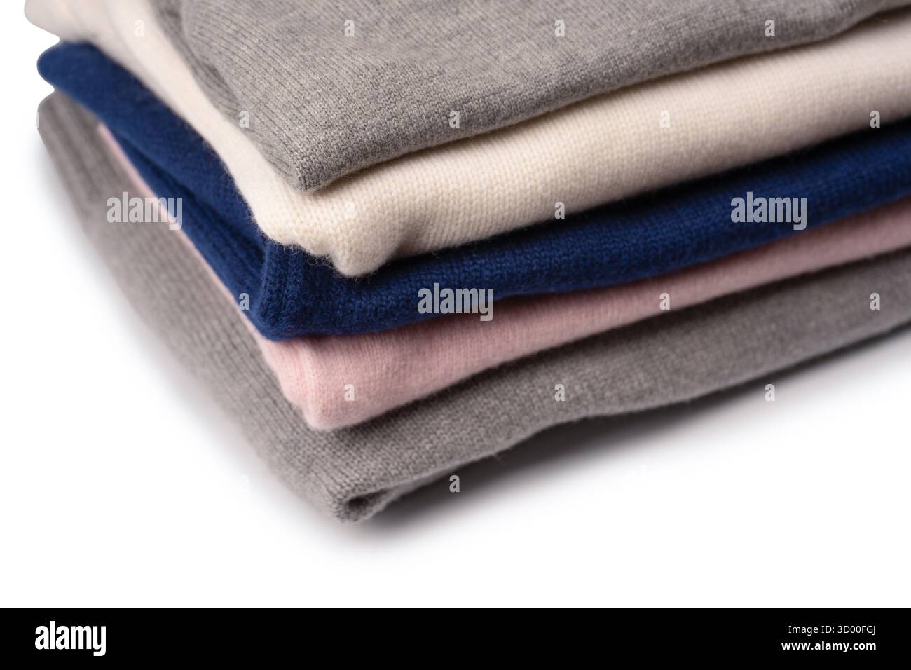 Eine Gruppe warmer Pullover auf weißem Hintergrund. Stapel gefalteter Pullover auf weißem Hintergrund. Stockfoto