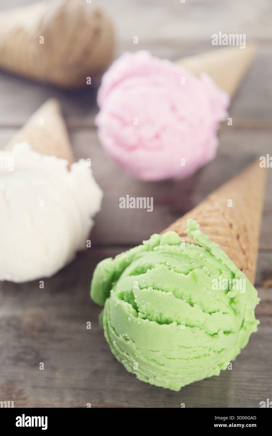 Verschiedene Eissorten in Waffeln auf rustikalem Holzhintergrund Stockfoto