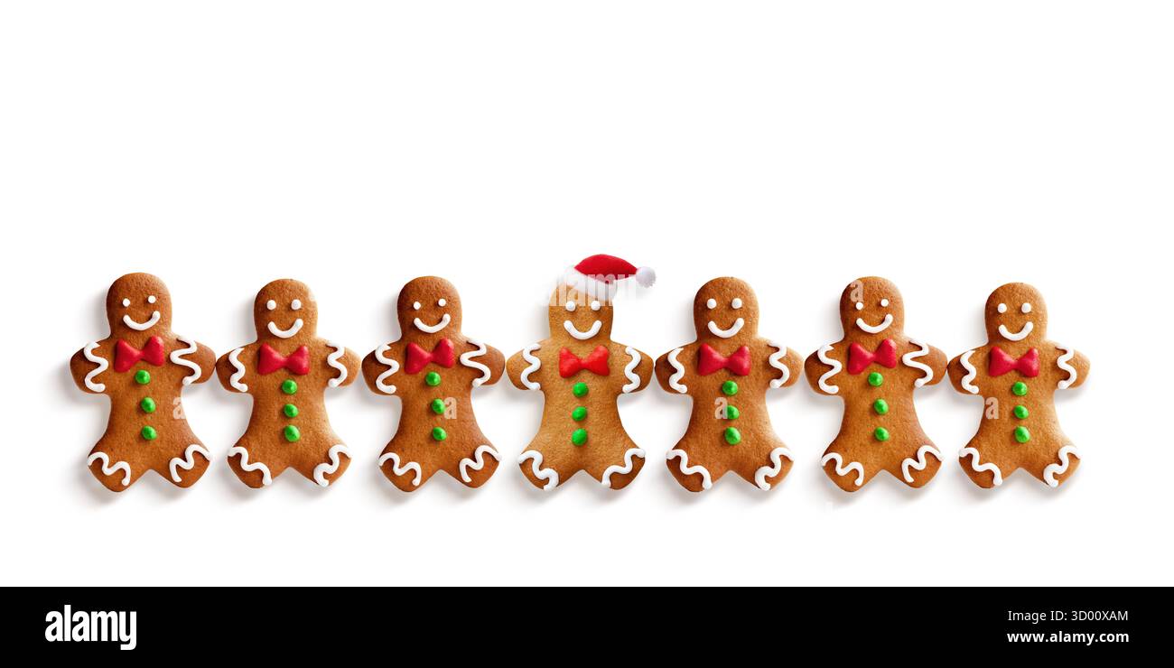 Lebkuchenkekse in Reihe mit Weihnachtsmütze auf weißem Hintergrund Stockfoto