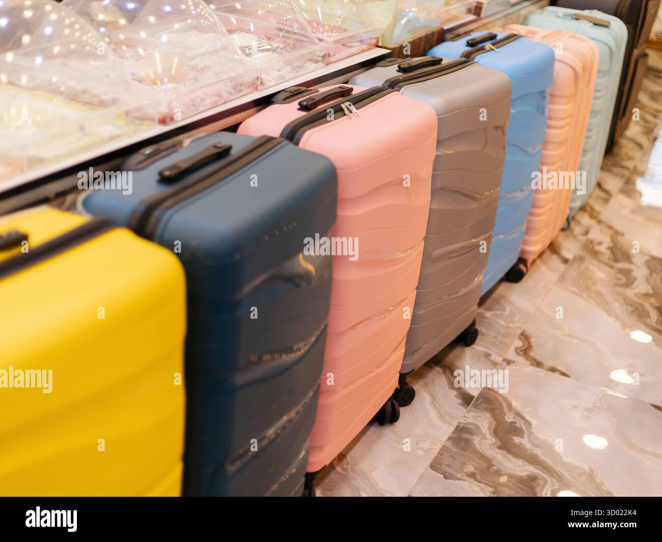 Bunte Koffer sind in einem Geschäft ordentlich angeordnet und bieten eine Vielzahl von Stilen und Farben. Käufer finden hier die perfekten Reiselösungen Stockfoto