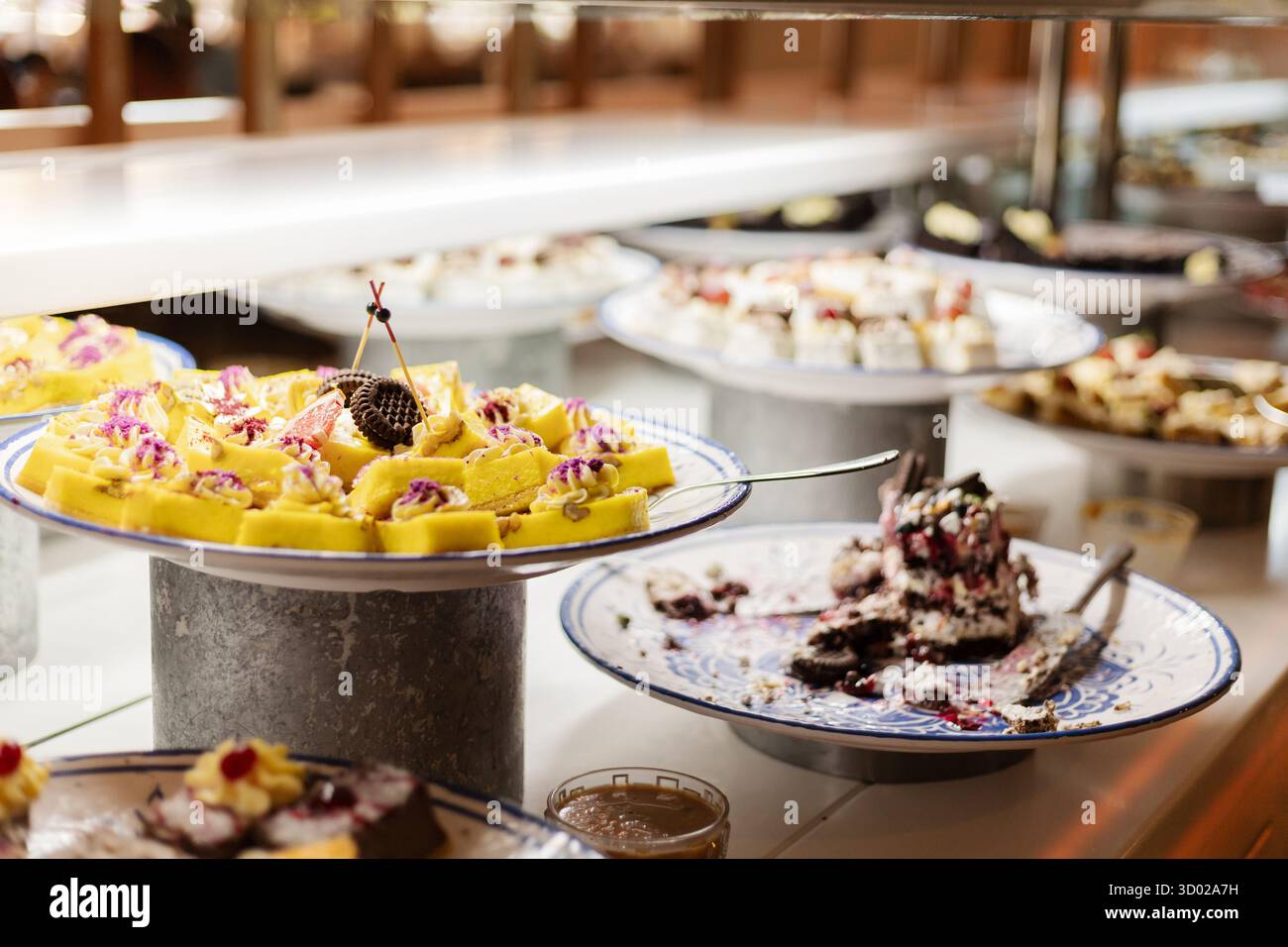 Ein lebhaftes Dessertbuffet bietet verschiedene Süßigkeiten, darunter Kuchen und Gebäck, die wunderschön auf silbernen Tellern angeordnet sind, um die Gäste zu genießen Stockfoto