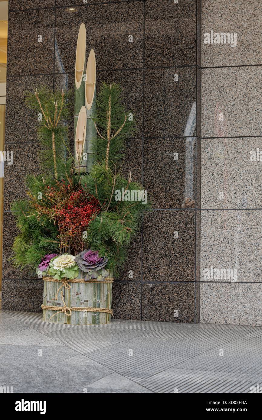 Kadomatsu aus drei schräg geschnittenen Bambusstielen und üppigen Kiefernzweigen mit blühendem Grünkohl schmückt den Gebäudeeingang während der Silvesterferien. Stockfoto