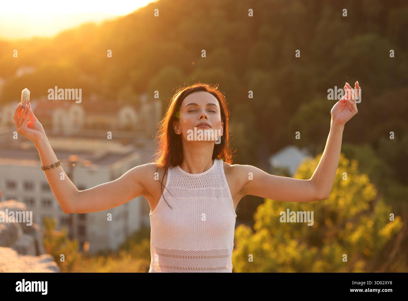 Frau, die mit Kristall meditiert, um ihre Aura im Freien zu heilen oder wiederherzustellen Stockfoto