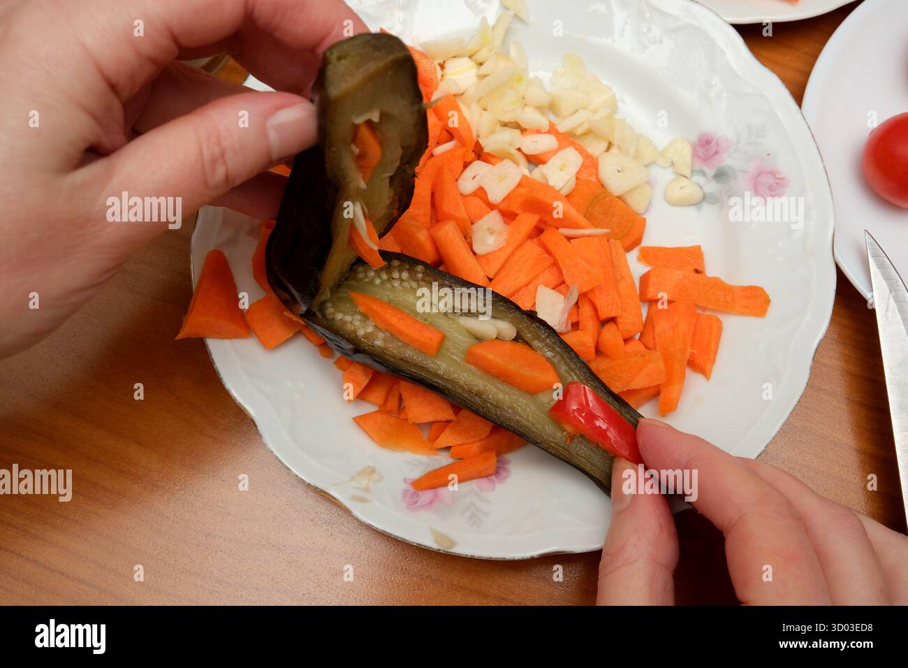 Hacken Sie buntes Gemüse wie Karotten und Knoblauch für eine köstliche Mahlzeit zu Hause. Stockfoto