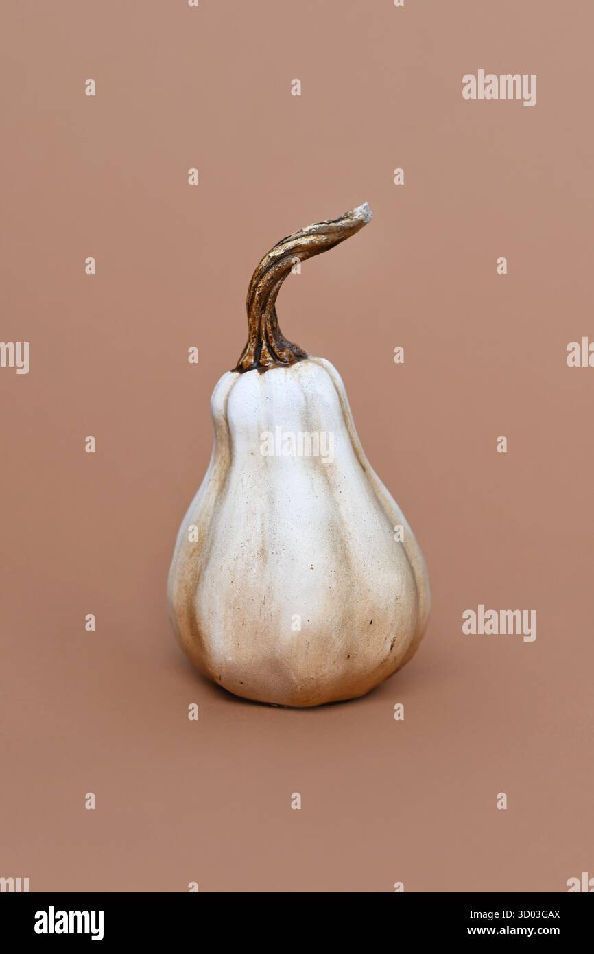 Einzelnes keramisches Kürbisschmuck auf braunem Hintergrund. Minimales Dekorationsobjekt im Herbst Stockfoto