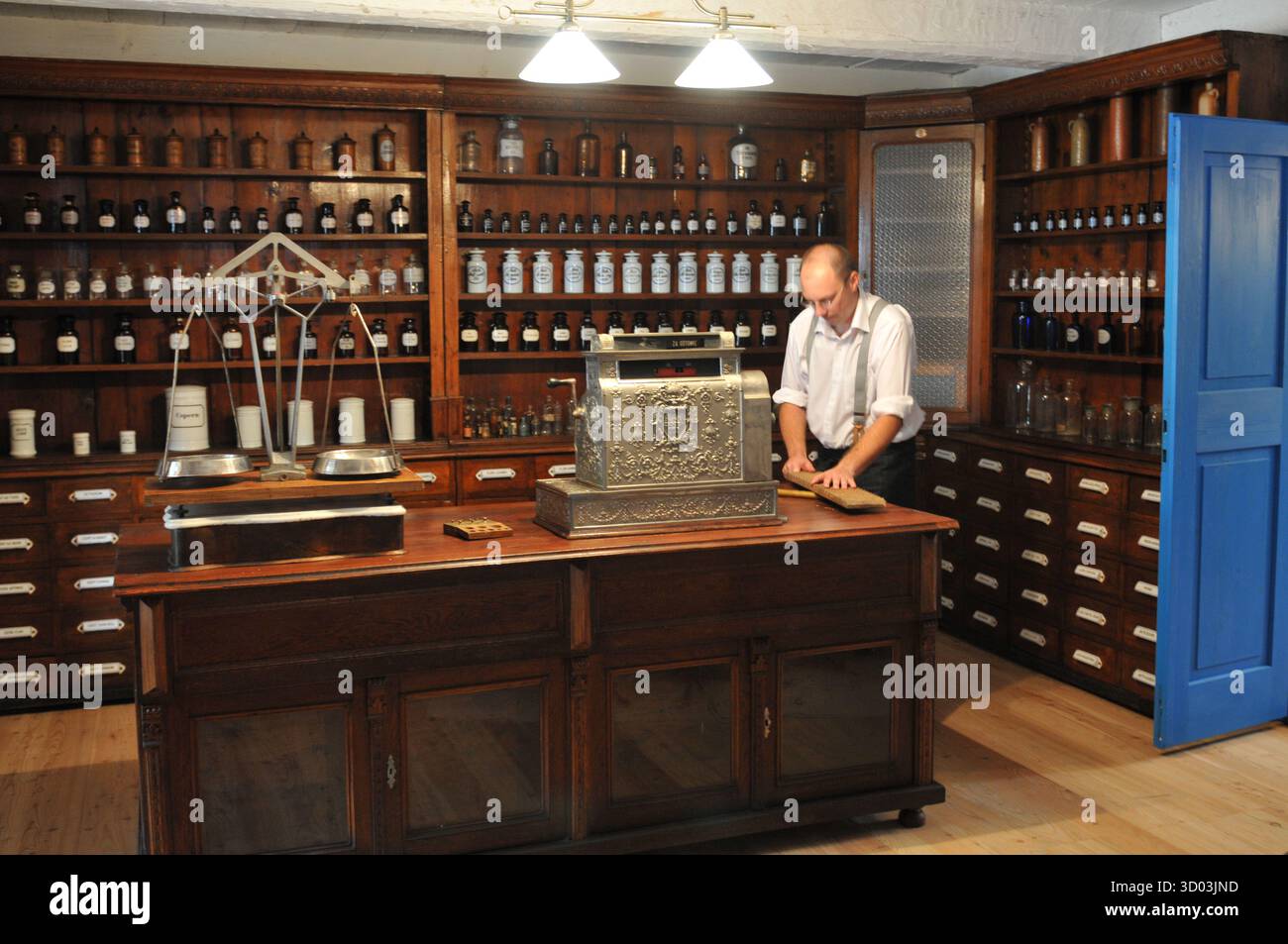Apothekerreenaktor, der handgemachte Wachskerzen in einer historischen Apotheke im Museum für Volksarchitektur in Sanok, Polen, einhüllt. Stockfoto