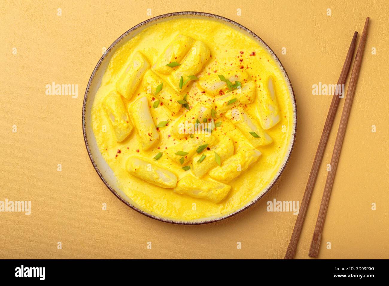 Köstliche koreanische tteokbokki-Reiskuchen in einer cremigen Käsesauce, garniert mit grünen Zwiebelscheiben, in einer Schüssel mit Essstäbchen, authentisches koreanisches Essen Stockfoto Köstliche koreanische tteokbokki-Reiskuchen in einer cremigen Käsesauce, garniert mit grünen Zwiebelscheiben, in einer Schüssel mit Essstäbchen, authentisches koreanisches Essen Stockfoto