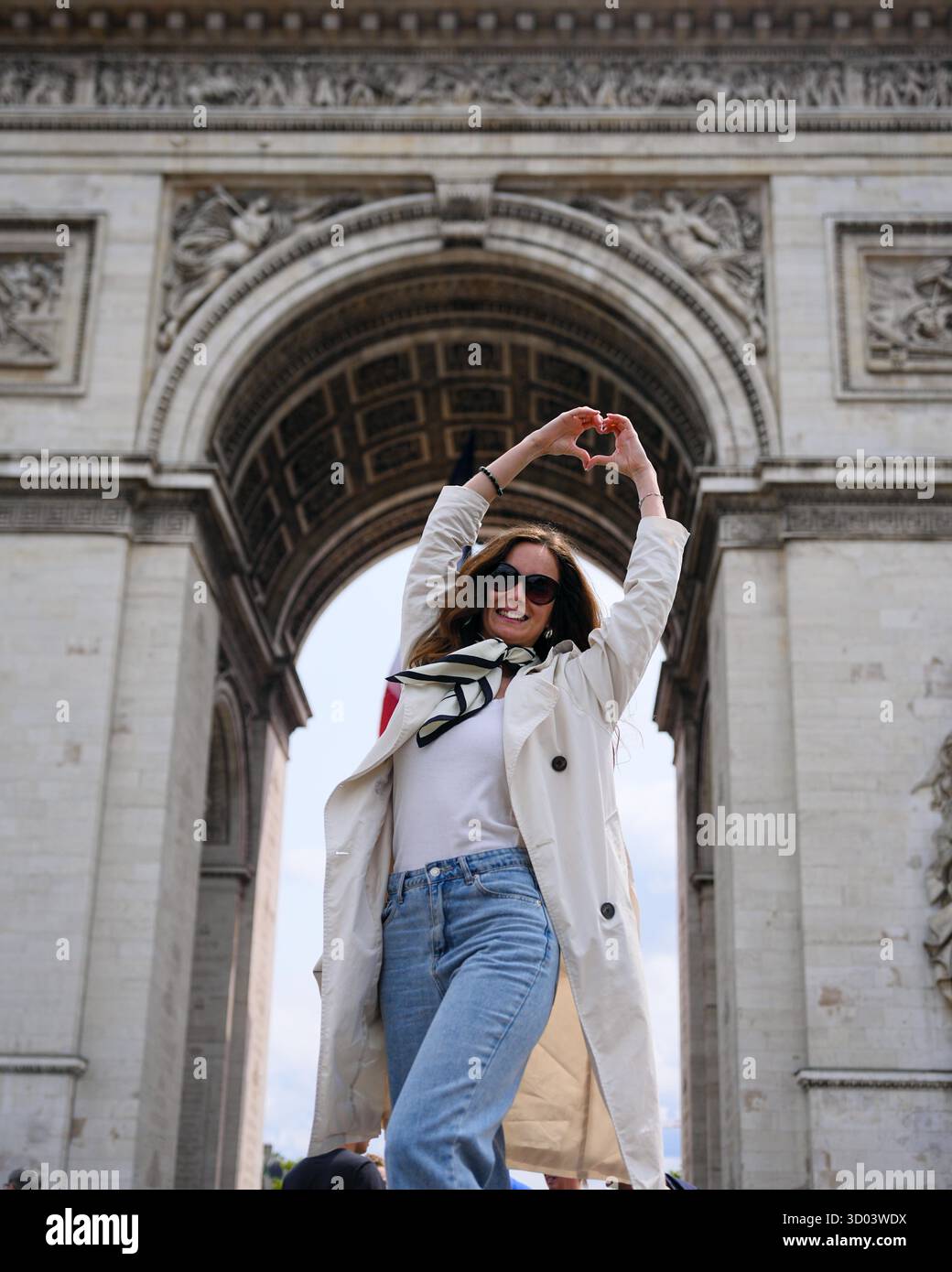 Fröhliche Frau in lässigem Outfit in der Nähe des Arc de Triomphe in Paris, Frankreich, mit erhobenen Händen an einem Sommertag || Model veröffentlicht Stockfoto