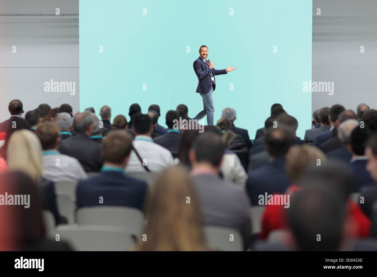 Mann, der auf der Bühne mit einem Mikrofon vor dem Publikum spricht Stockfoto