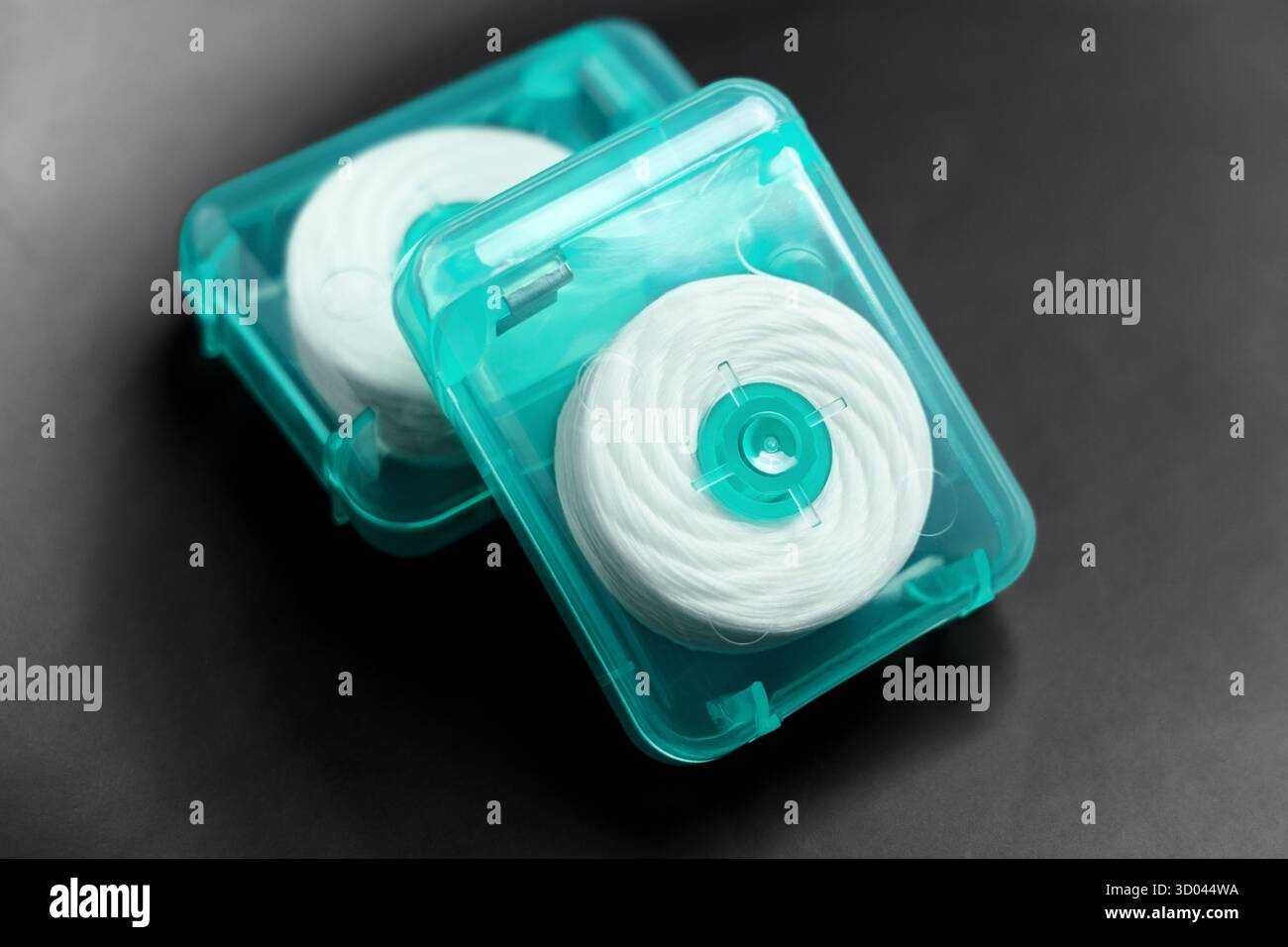 Zahnseide in grünen Kunststoffbehältern auf schwarzer Keramik-Nahaufnahme Stockfoto