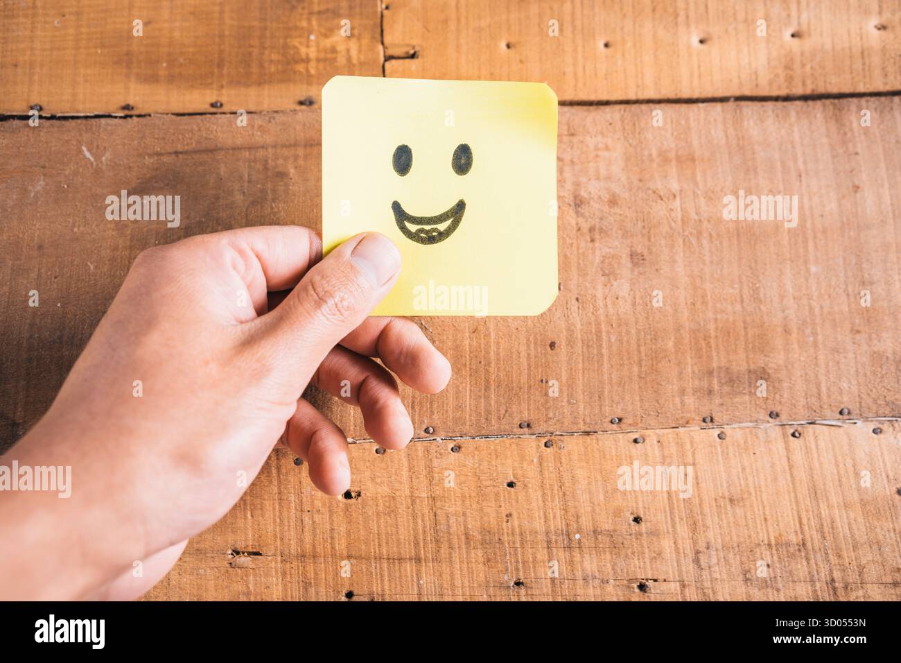 Die Hand einer Frau, die eine farbige Karte hält, auf der ein Gesicht gezeichnet ist, symbolisiert eine Chance oder ein Konzept für den Geschäftserfolg Stockfoto