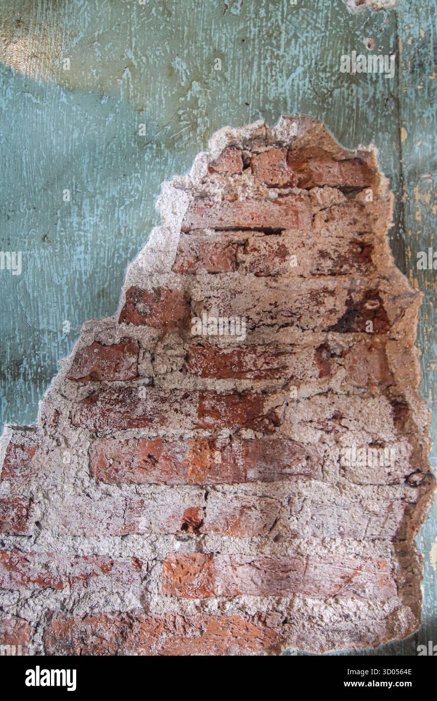 Distressed Ziegelwand Textur mit abziehendem Teal/Aqua Putz. Grober Hintergrund für architektonische Details, Geschichte oder urbane Verfallskonzepte. Stockfoto