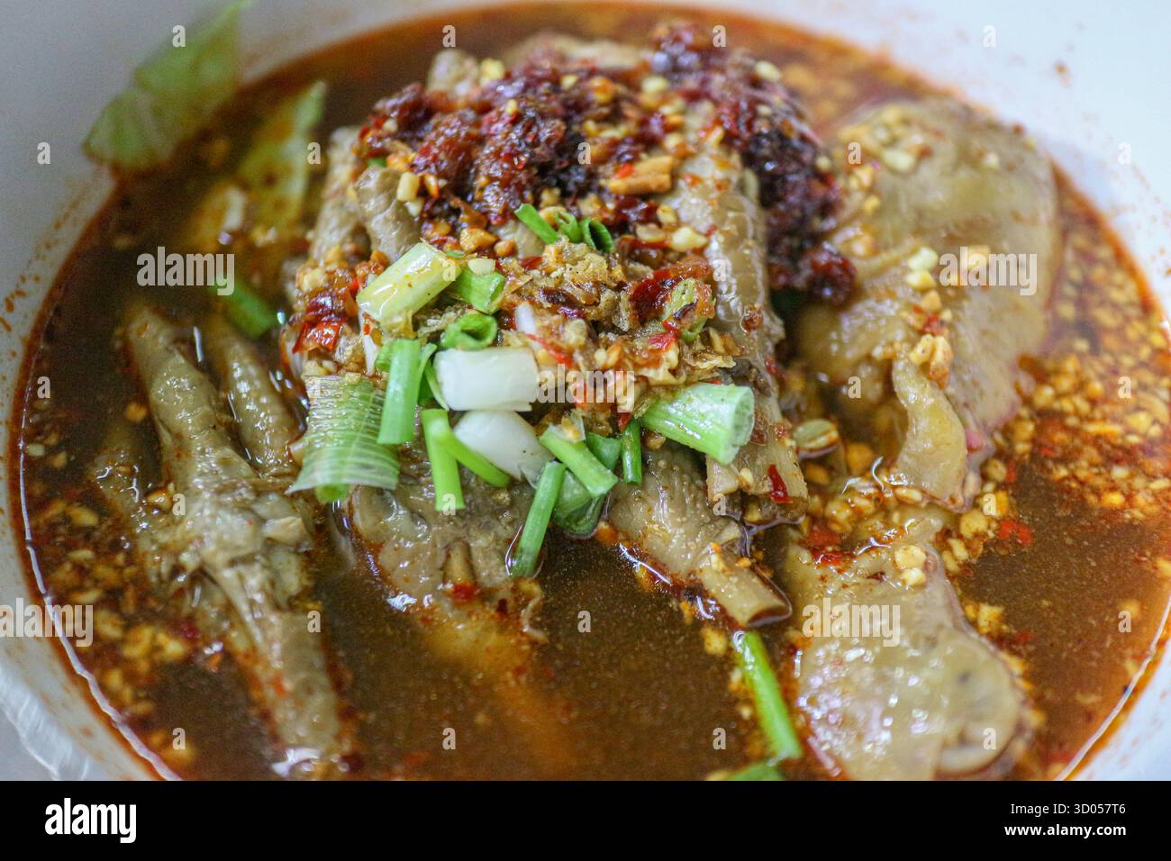 Nahaufnahme von Hähnchenfüßen in reichhaltiger, scharfer Thai Nudelsuppe (Guay Teow Gai Mara). Konzentrieren Sie sich auf Brühe, Textur und authentisches Street Food. Stockfoto