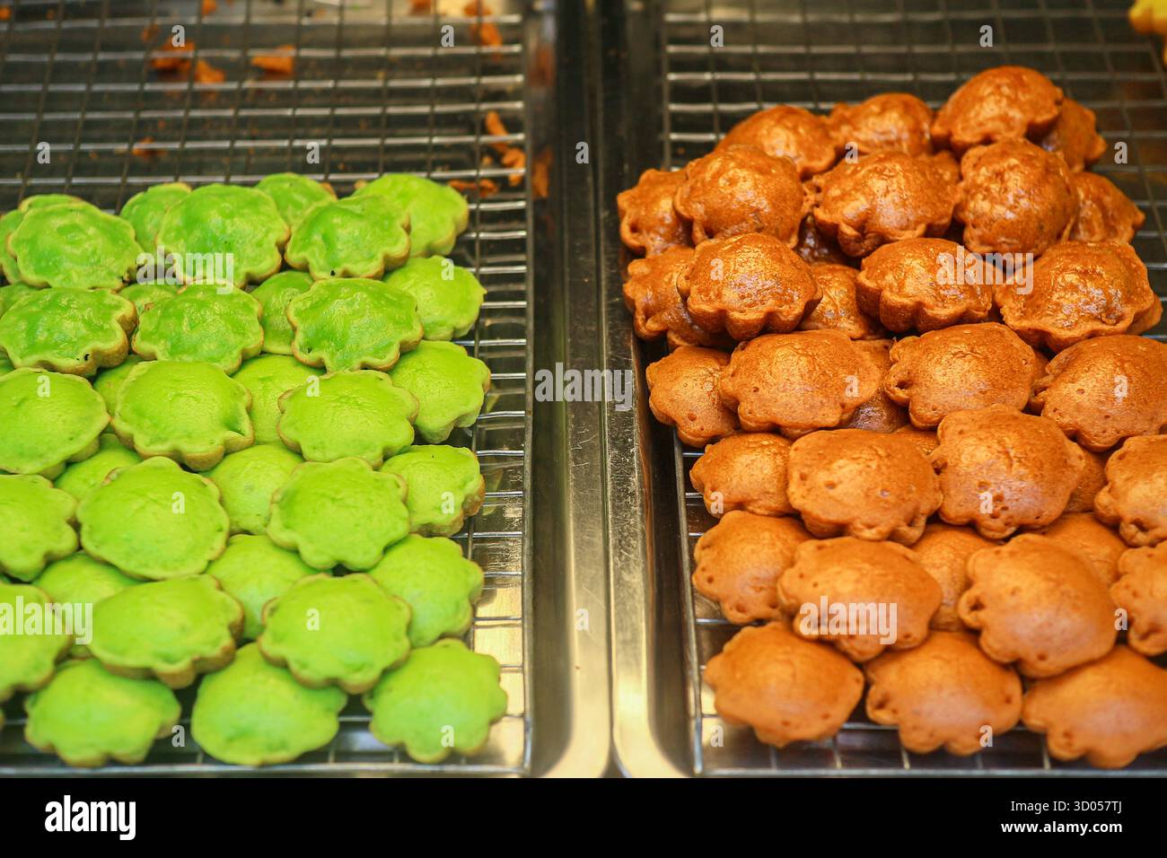 Kanom Krok (Thai Coconut Pancakes) in Pandan- und Thai-Tee-Aromen. Beliebtes, warmes thailändisches Streetfood-Dessert und moderner asiatischer süßer Snack. Stockfoto