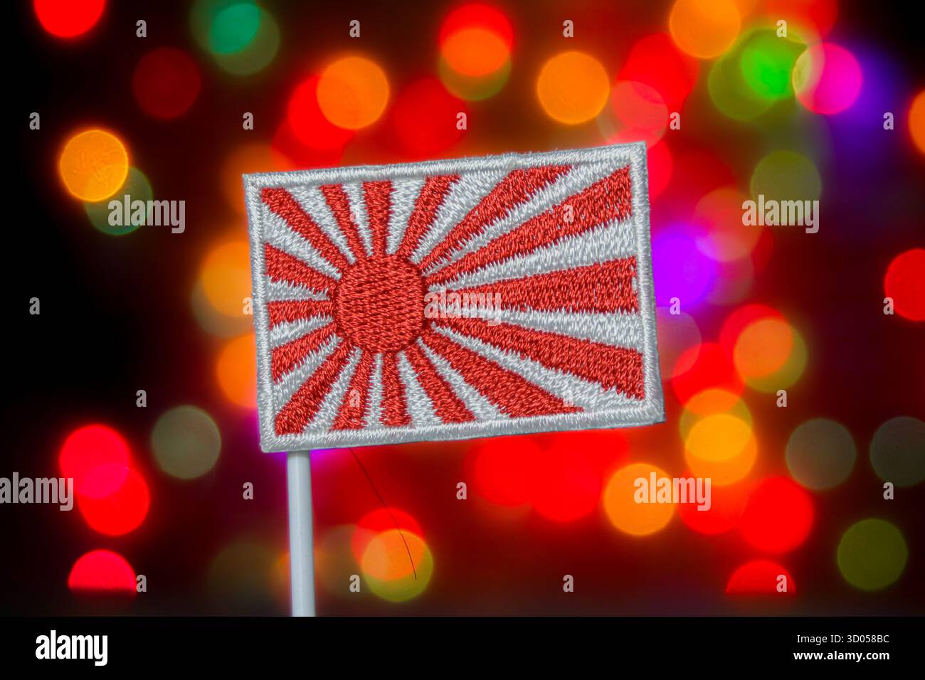 Japanische Flagge der aufgehenden Sonne vor bunten Bokeh-Lichtern. Asiatische Kultur, japanische Geschichte, traditionelles Symbol und festliche Medien. Stockfoto