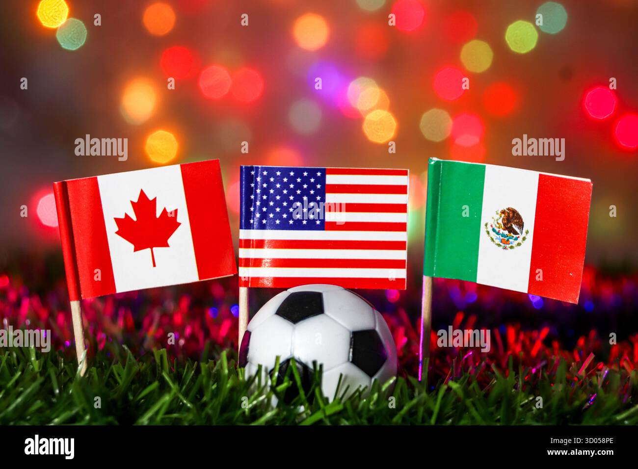 Fußball mit Fahnen von Kanada, USA und Mexiko auf Gras gegen festliches Bokeh. Großes globales Ereignis, nordamerikanische Gastgeber und Sportfest. Stockfoto