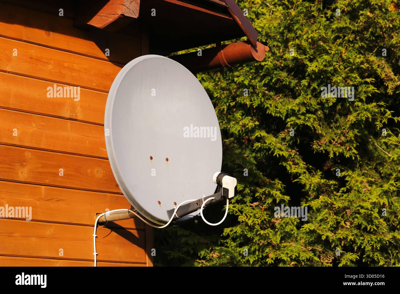 Satellitenschüssel an Holzwand. Empfangseinrichtung für Heim-TV. Hardware für Außenantennen. Digitale Signalanlagen an der Hausfassade. Kommunikationstechnologie. Stockfoto
