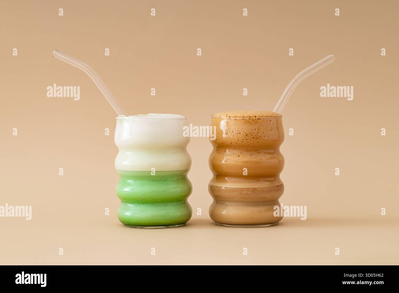 Matcha Latte und Kaffee vor beigefarbenem Hintergrund. Minimales Matcha vs. Kaffeekonzept. Trendige natürliche Energie und gesunde Getränke. Stockfoto